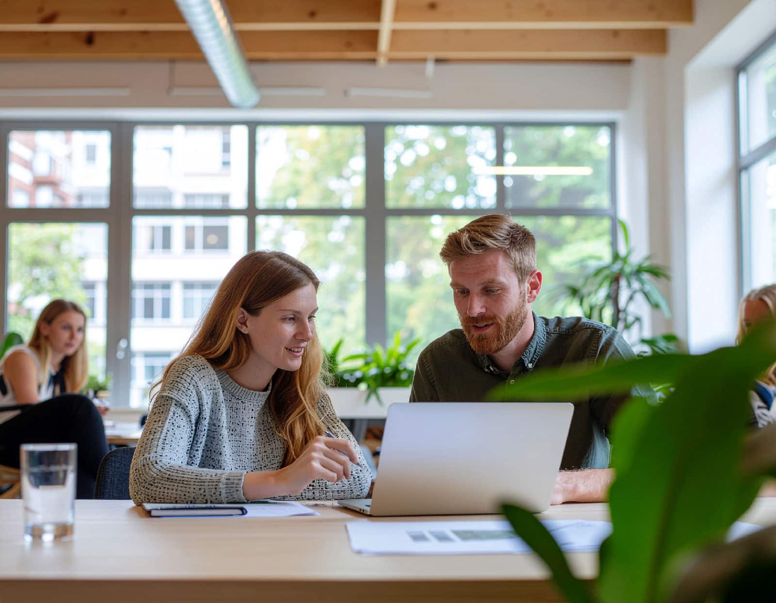 Två personer sitter i en modern kontorsmiljö framför en dator och arbetar med att ta fram en SEO-strategi för bättre synlighet i Google.