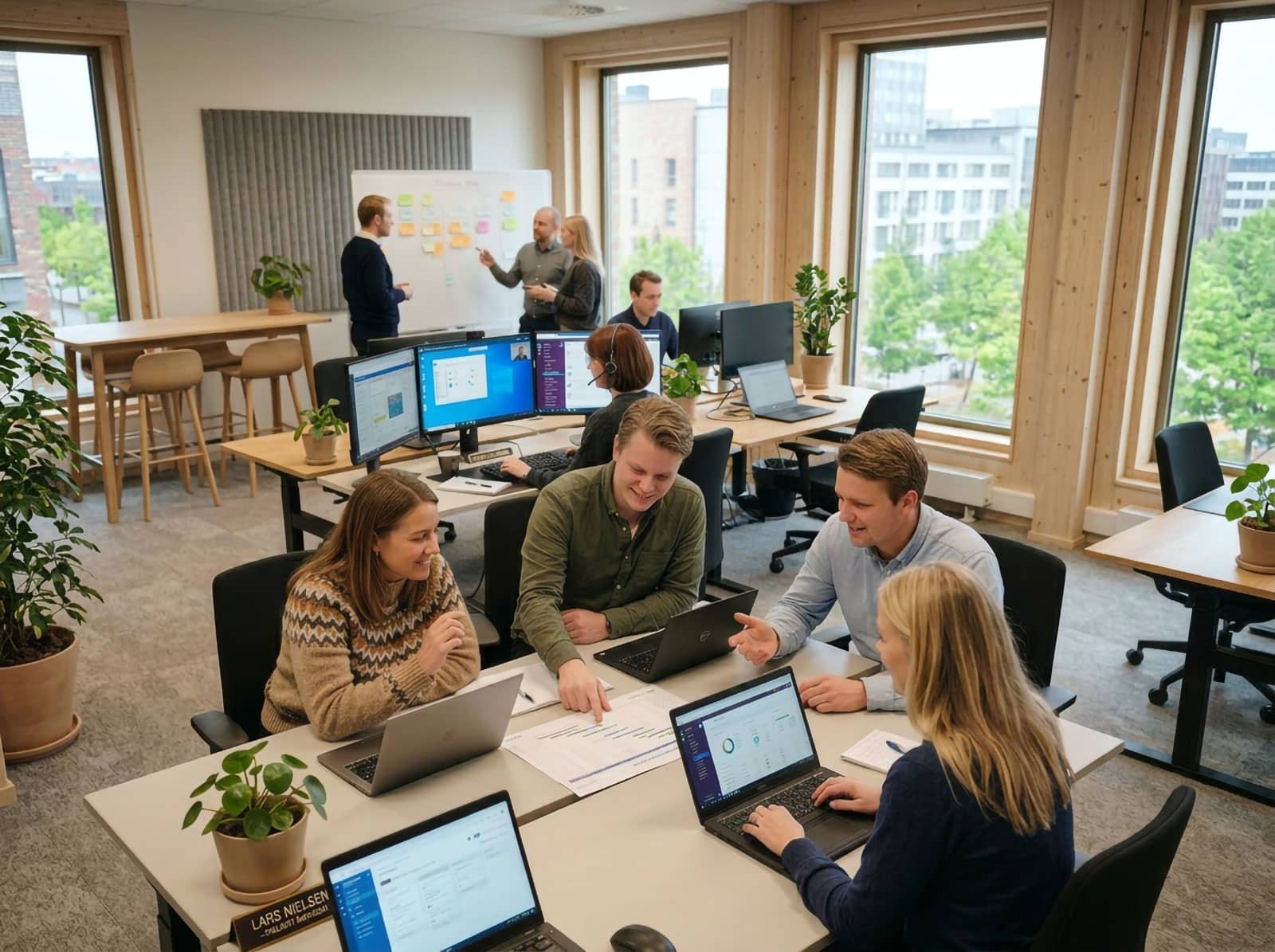 Medarbetare i modernt skandinaviskt kontor som samarbetar med digitala verktyg inför höststarten