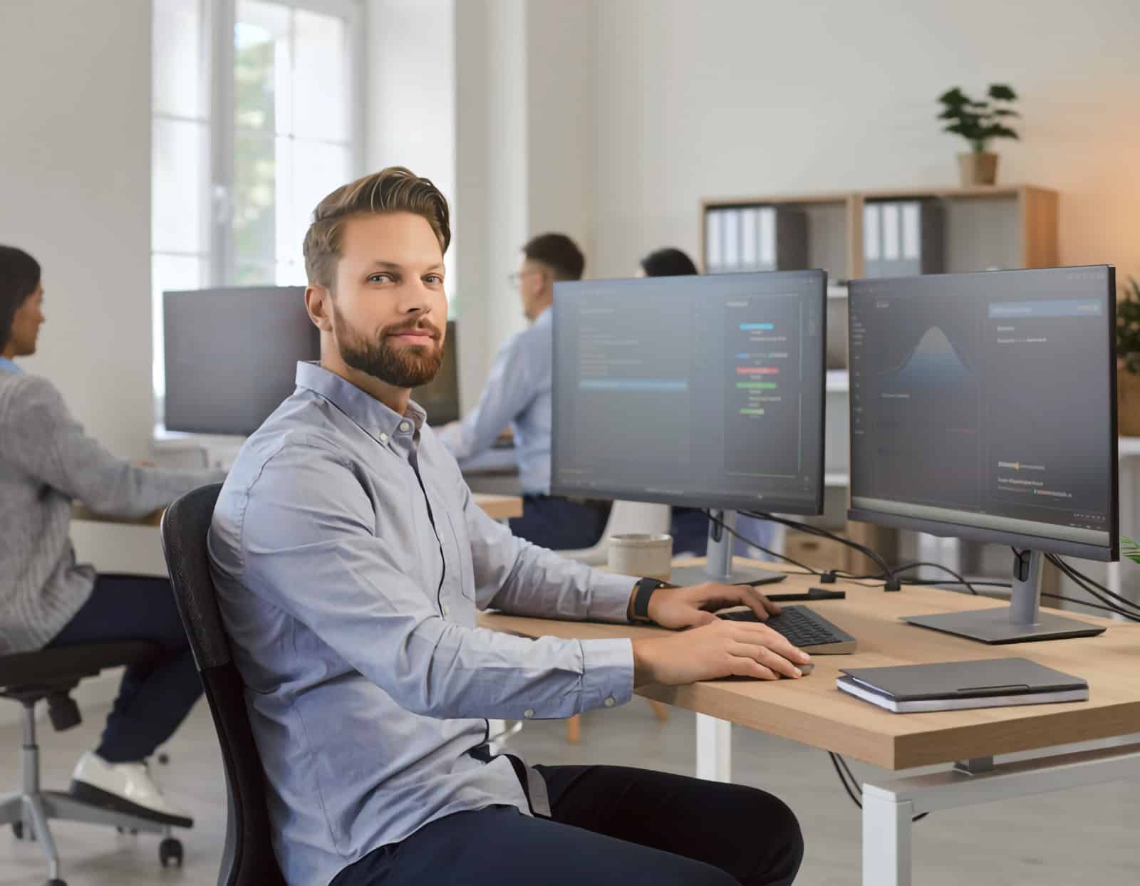 IT-specialist övervakar återställning av system medan medarbetare arbetar vidare i en modern kontorsmiljö.