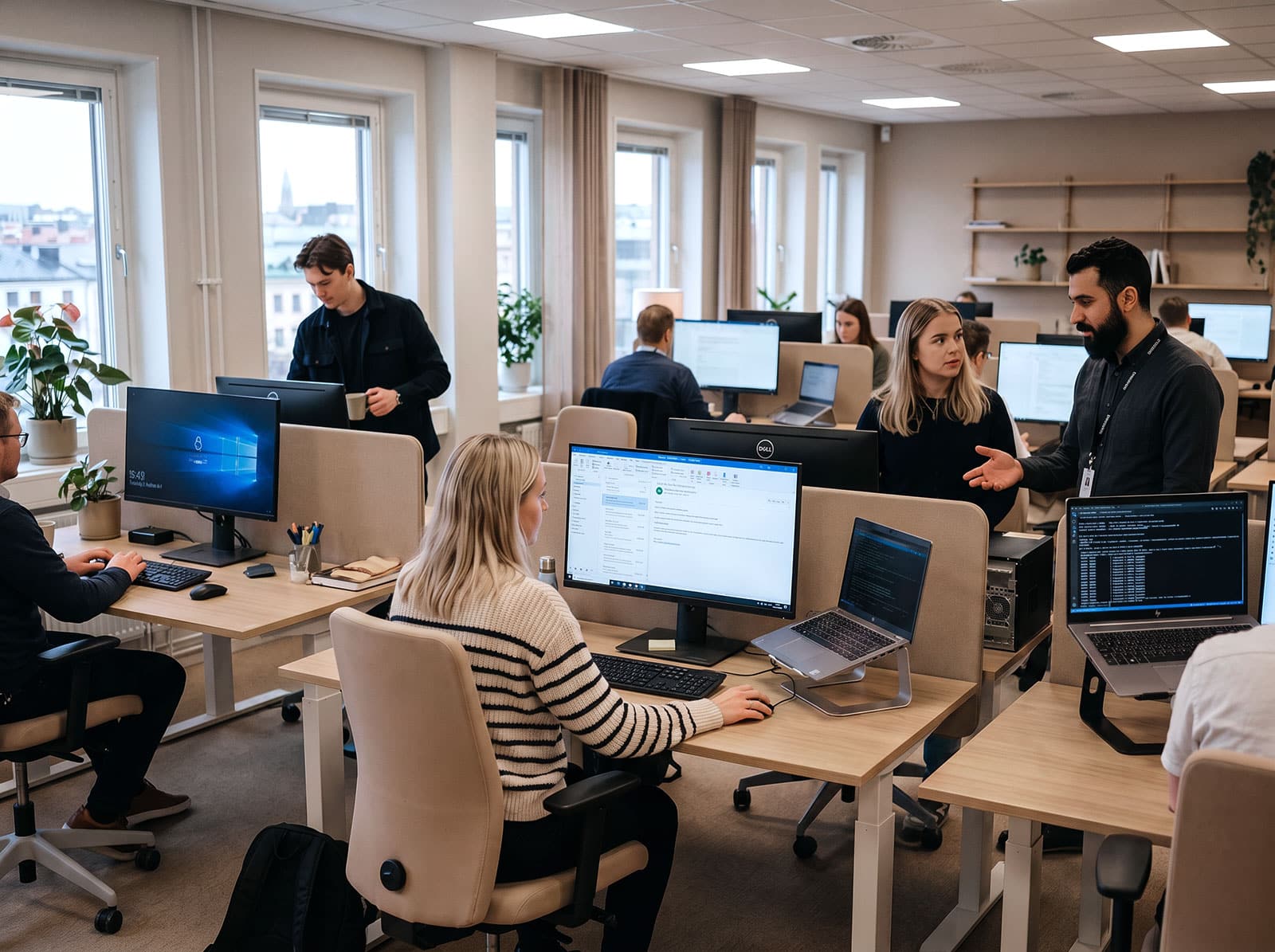 Medarbetare i ett modernt svenskt kontor arbetar tillsammans medan säkerhetsmedvetna rutiner och IT-stöd är en naturlig del av arbetsdagen.